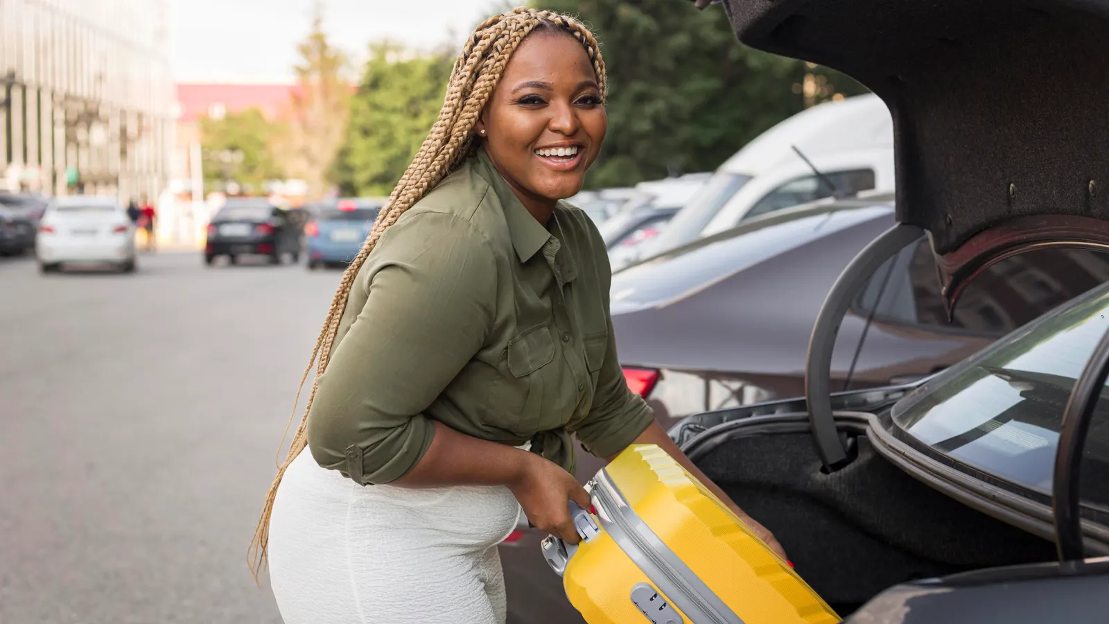 A traveller loading a suitcase into the boot of a hire car