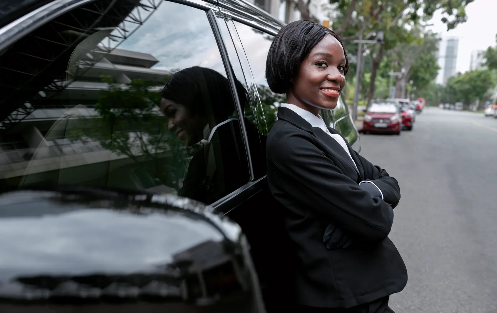 A Nii Plants chauffeur waiting beside a black hire car