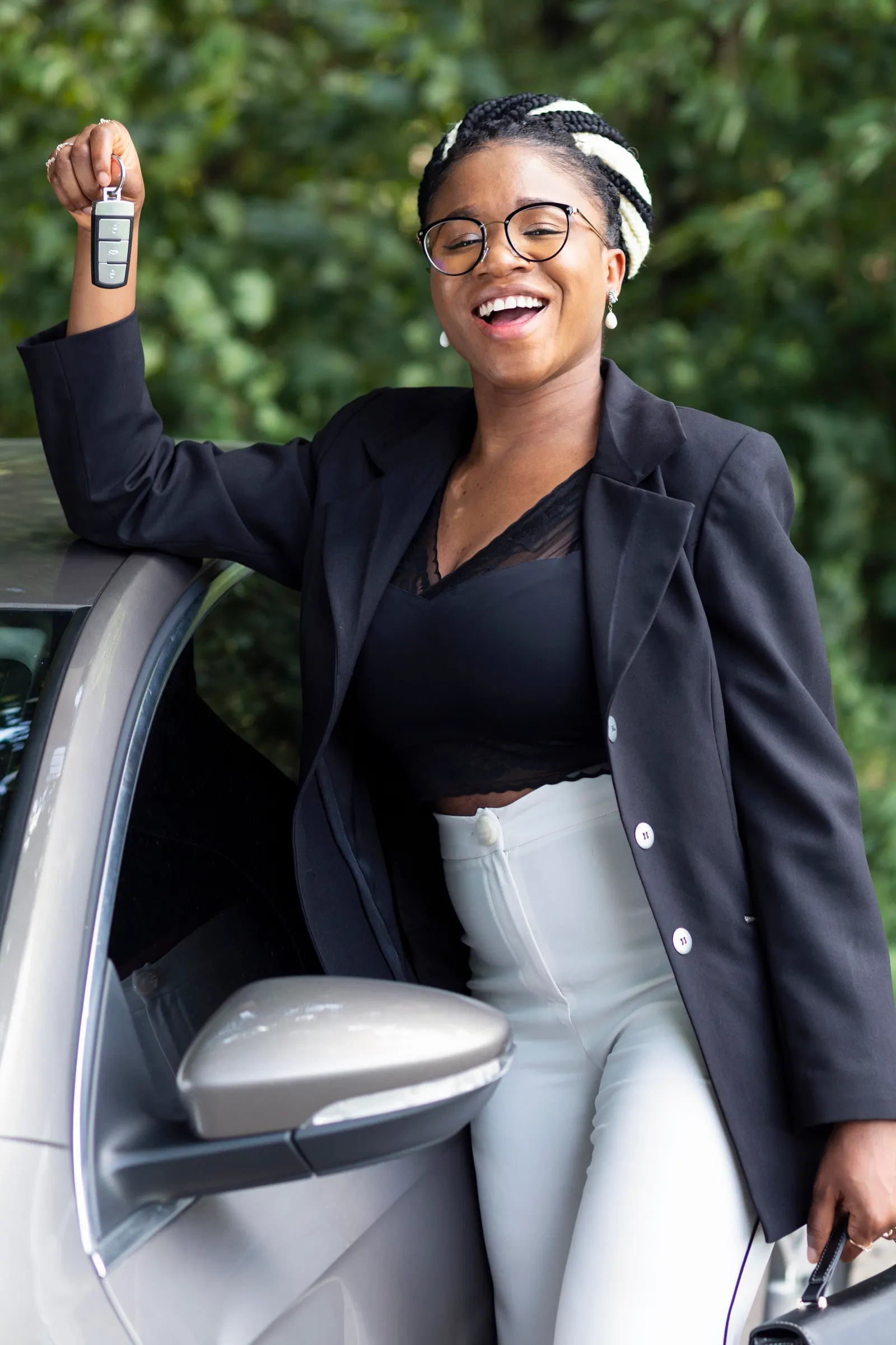 A customer holding car keys beside a Nii Plants hire car in Accra