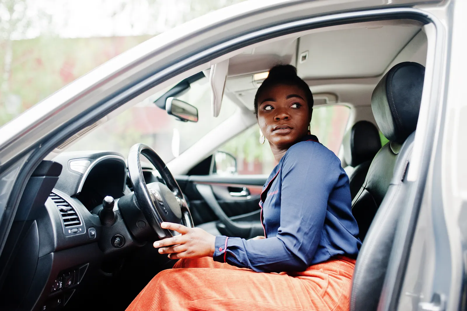 A driver at the wheel of a self-drive hire car, checking over her shoulder