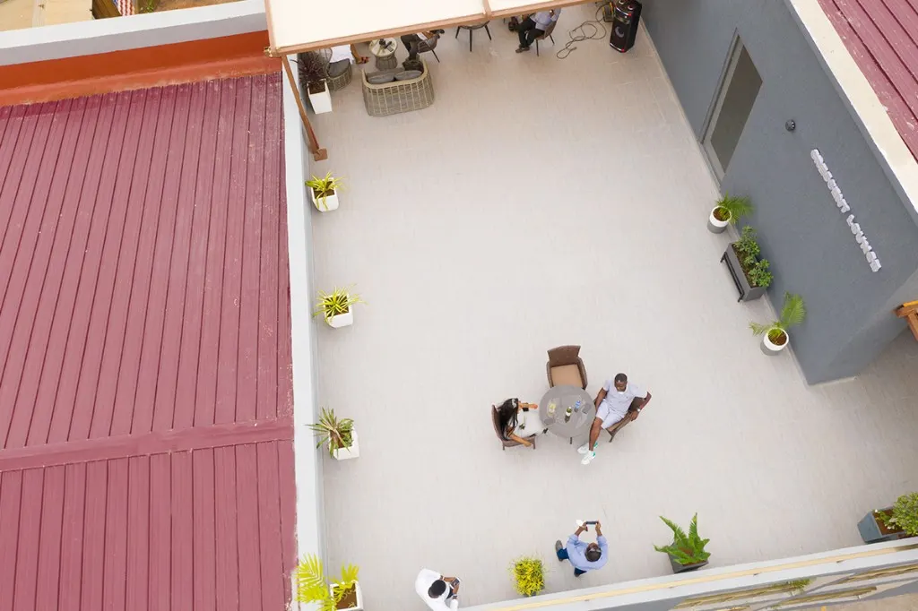 Aerial view of Crescent Lounge terrace at Plantsville in Dansoman, Accra, with tiled seating, planters, and the lounge name on the wall